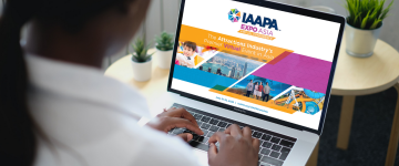 Woman looks at a laptop screen with details about IAAPA Expo Asia Virtual Conference