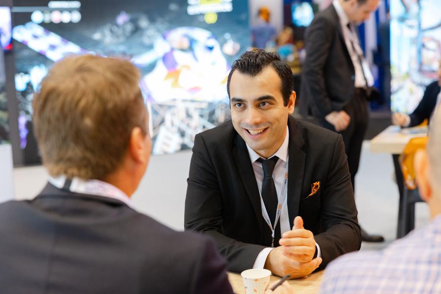 Two business men facing in opposite positions, discussing business proposals at a trade show booth during IAAPA Expo