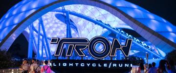 El letrero Tron Lightcycle Run frente a la atracción iluminado por la noche.