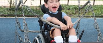 A child in a wheelchair plays on an accessible swing at Morgan's Wonderland water park