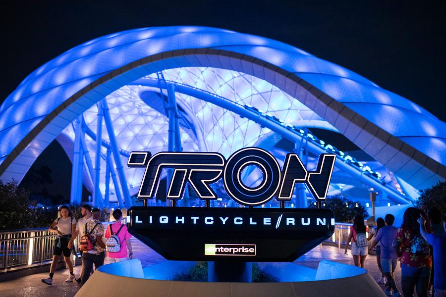 The Tron Lightcycle Run sign in front of the attraction illuminated at night.