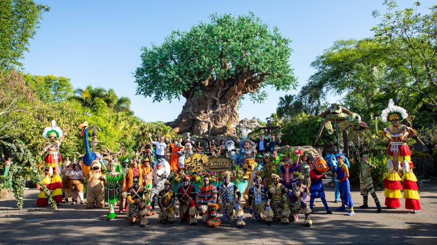 Collection of performers poses in front of the Tree of Life following a 25th anniversary performance