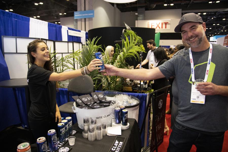 Woman at White Claw booth hands man a drink.