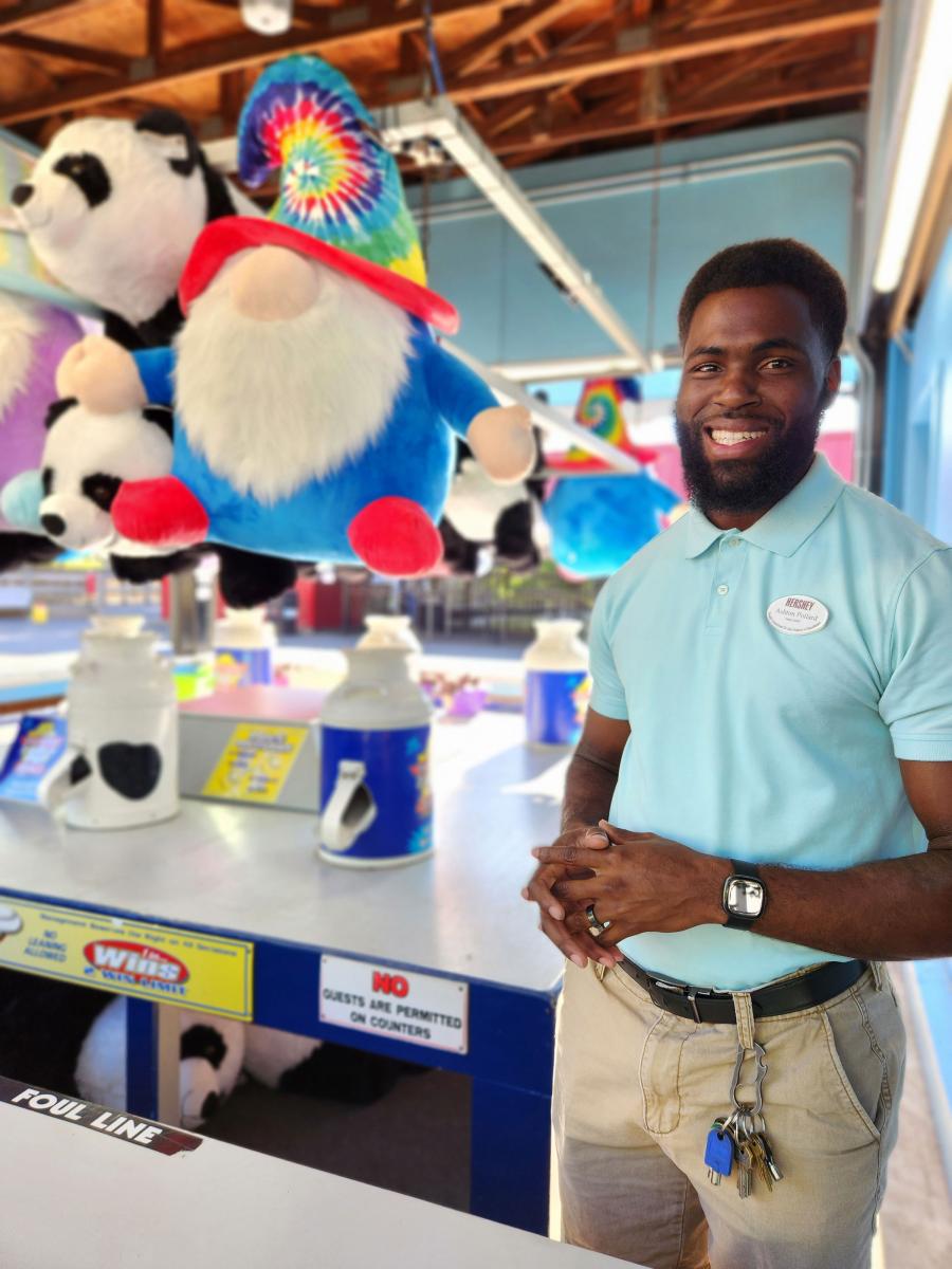An employee of Hersheypark poses next to the midway prizes offered inside the chocolate brand theme park