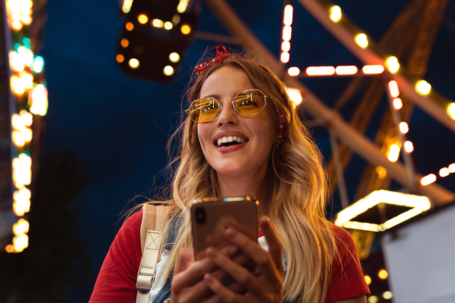 Smiling girl with phone at theme park 