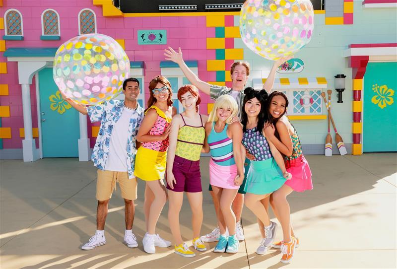A group of entertainers in summer beach wear costumes pose for a promotional image for Merlin Entertainments 