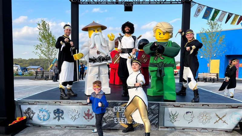 A kid poses with performers from Lego Ninjago: Ceremony of the Elements stage show at Legoland Resort