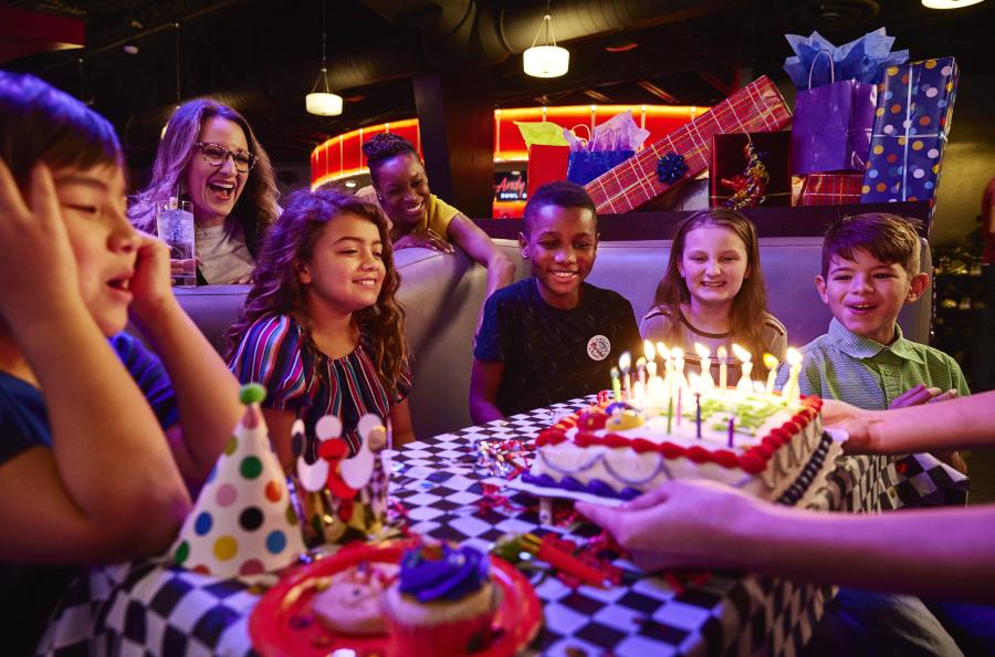 Andy B's organizza una festa di compleanno con una torta e bambini sorridenti.