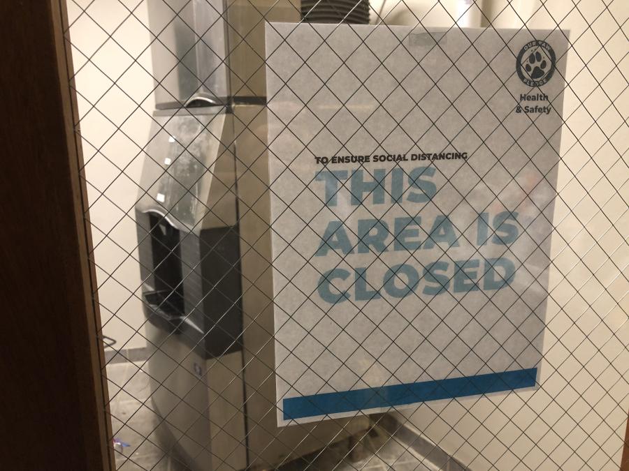 Sign saying that This Area is Closed on a door window--ice machine is visible in the background.