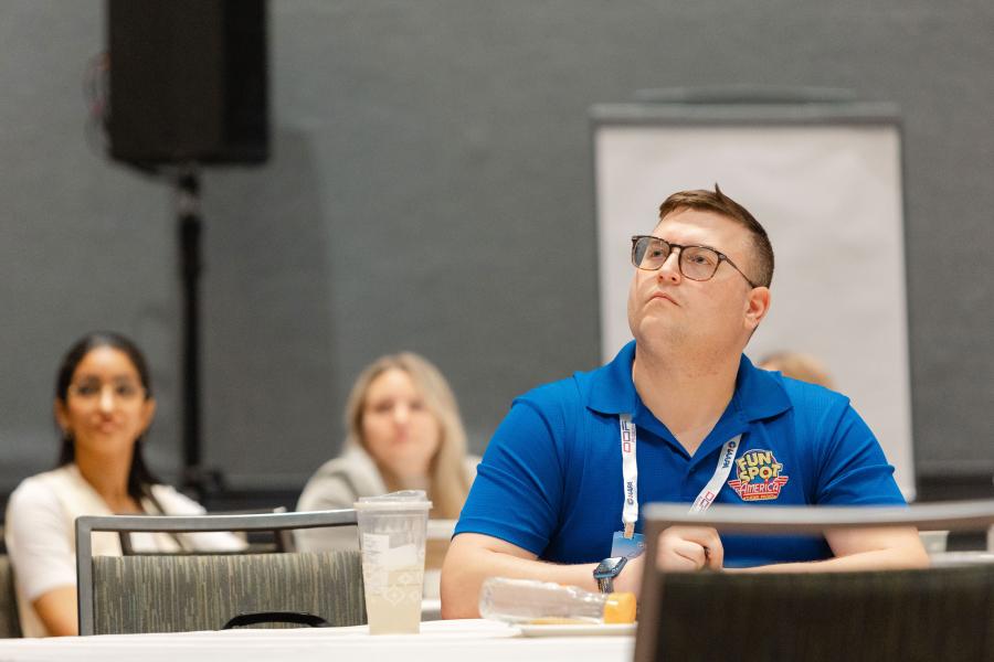 An attendee wearing a FunSpot company polo is paying close attention to the IAAPA Institute for Attractions Professionals seminar at IAAPA Expo 2023