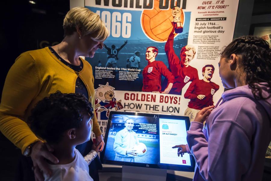 Una donna e due bambini toccano lo schermo di una mostra interattiva.