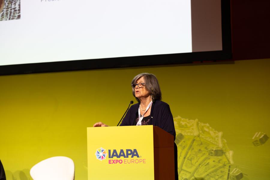 Anna Grazia Laura, présidente du Réseau européen du tourisme accessible, debout sur un podium pour présenter l'importance du tourisme accessible lors de l'IAAPA Expo Europe 2023