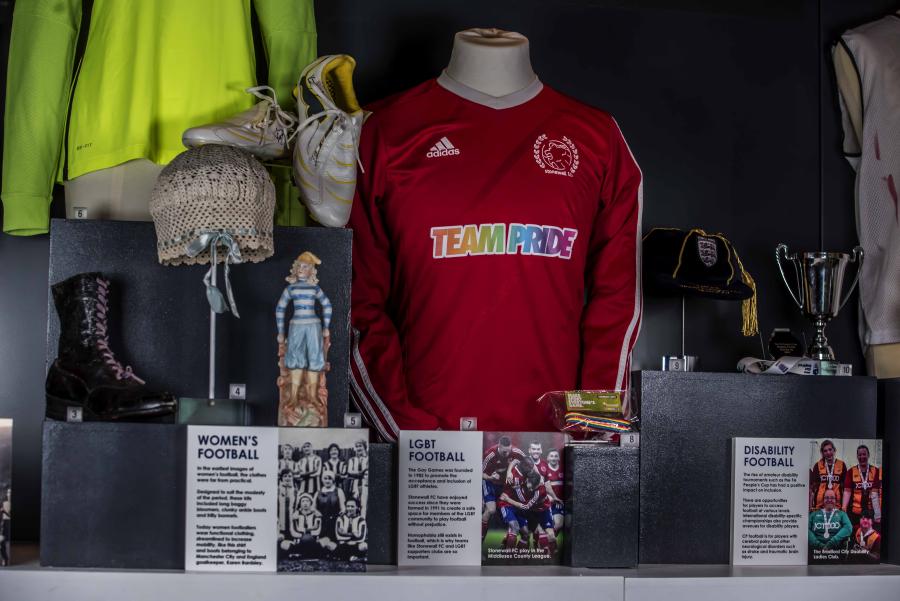Exhibit on LGBTQ+ soccer players is on display in a case.