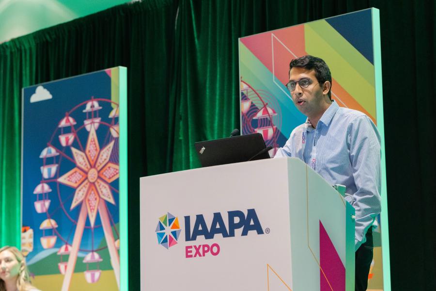 Le conférencier Anil Rao est debout sur un podium lors de la session EDUSe sur la santé opérationnelle : comment l'efficacité de la main-d'œuvre et des déchets favorise la durabilité et la rentabilité à l'IAAPA Expo 2023.