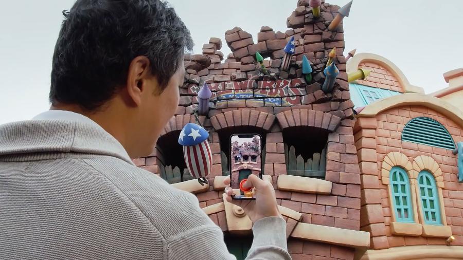 Illumix AR 技术的演示，一名男子在迪士尼乐园的卡通镇地区使用他的智能手机