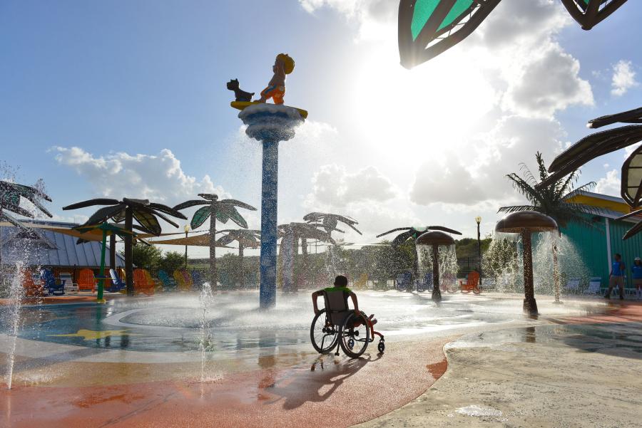 A water park guest in a wheelchair in the splash pad playground inside Morgan's Wonderland