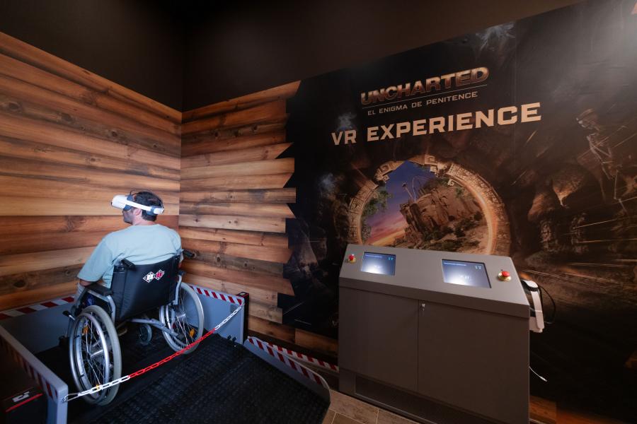 A person in a wheelchair wearing a virtual-reality headset in a designated area for the Uncharted: The Enigma of Penitence attraction at PortAventura