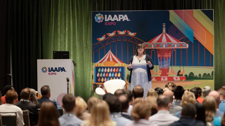 Relatore Lauren Tidmore, Ed.D. è in piedi su un podio durante la sessione EDUS Fix Your Trainwreck tenutasi all'IAAPA Expo 2023
