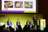 Panelists on stage with a PowerPoint slideshow on a projector screen showing food and beverage offerings as example during F&B Innovations panel at IAAPA Expo Europe