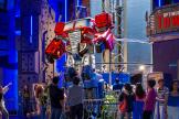 Los visitantes señalan y miran la atracción Optimus Prime Tower dentro de Hasbro City