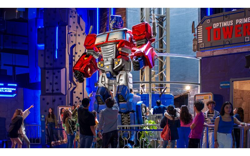 Visitantes apontam e olham para o passeio Optimus Prime Tower dentro da Hasbro City